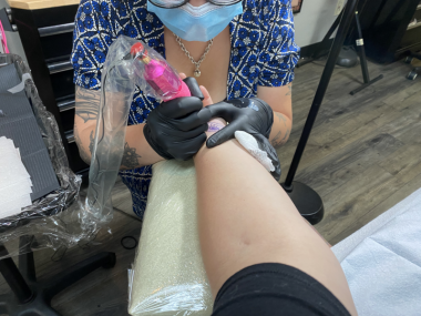 Tattoo artist Brie Gordon tattoos Jamie's left wrist.