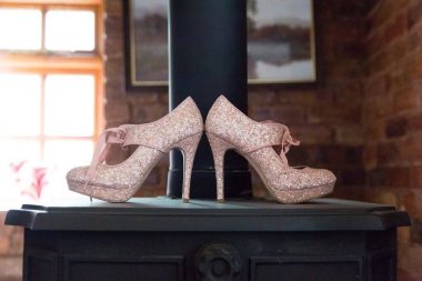 heels and MS | Multiple Sclerosis News Today | A pair of pink, glittery high heels are displayed on a platform, with a brick wall and sunlit window in the background.