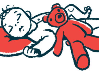 A red teddy bear lies against the side of a sleeping infant.