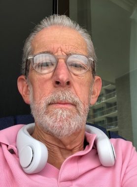 tips on staying cool in the summer heat | Multiple Sclerosis News Today | A close-up selfie shows Ed in a pink shirt, with a new neck fan.