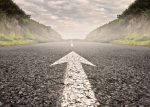 primary progressive MS | Multiple Sclerosis News Today | A stock photo of a long road with a white arrow pointing toward the horizon.