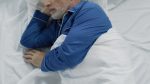 MS fatigue | Multiple Sclerosis News Today | A stock photo of a man wearing blue pajamas and sleeping in bed.