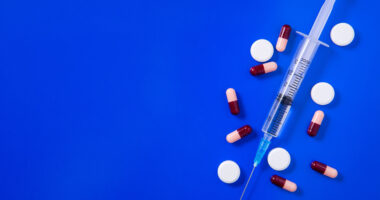 an injection shot and pills on a blue background