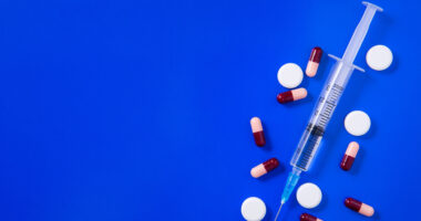 an injection shot and pills on a blue background