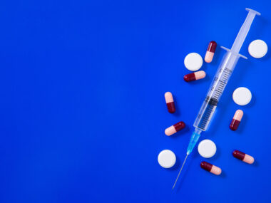 an injection shot and pills on a blue background