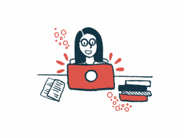 A person seated at a table uses a computer with a stack of books next to it.