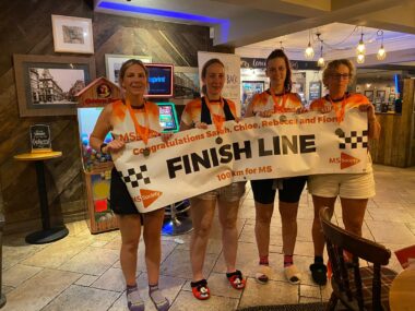 A group of women hold a banner reading "finish line." 