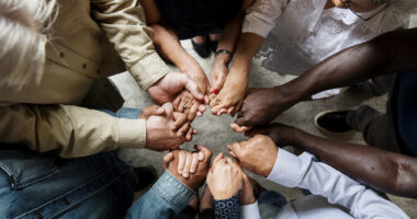 A group of people in a huddle with their hands placed in the middle.