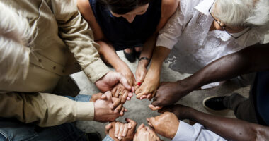 A group of people in a huddle with their hands placed in the middle.