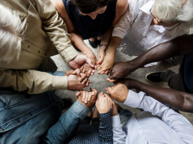 A group of people in a huddle with their hands placed in the middle.