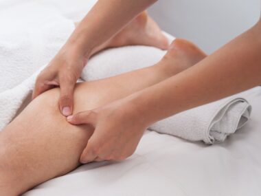 A massage therapist massages a patient's calf muscle to ease spasticity.