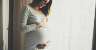 pregnant woman looking down and holding her stomach