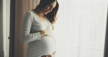 pregnant woman looking down and holding her stomach