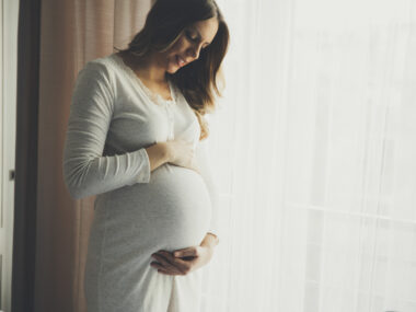 pregnant woman looking down and holding her stomach