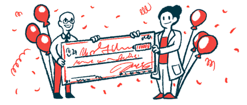 Two people, one in a white lab coat, each hold an end of an oversized check, flanked by balloons.