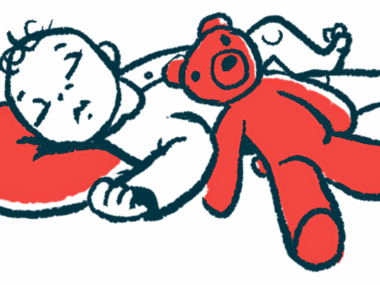 A red teddy bear lies against the side of a sleeping infant.