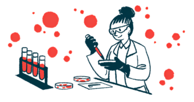 A scientist works with a petri dish in a lab, alongside a rack of four vials filled with liquid.