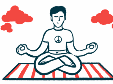 A person sits with their crossed legs on a striped mat with their hands in meditation position.