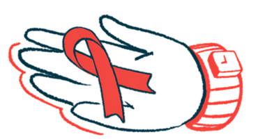 A hand holds a red awareness ribbon.