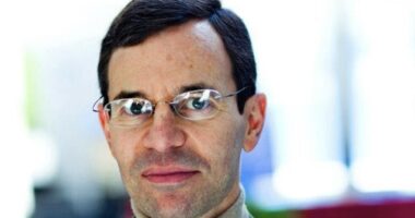 A headshot shows a man with dark hair and glasses.