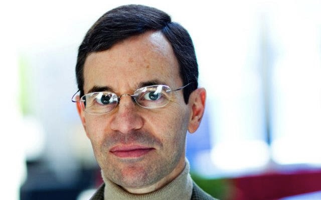 A headshot shows a man with dark hair and glasses.