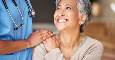 A smiling patient is being comforted by a doctor.