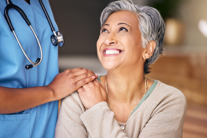A smiling patient is being comforted by a doctor.