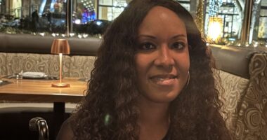 A closeup horizontal head shot of a woman sitting at a table in a restaurant.
