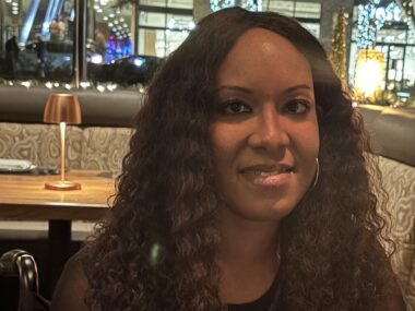 A closeup horizontal head shot of a woman sitting at a table in a restaurant.