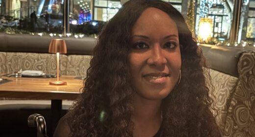 A closeup horizontal head shot of a woman sitting at a table in a restaurant.