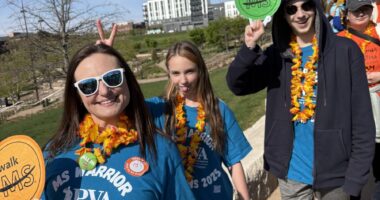 A mother, young daughter and young son, pose on a sunny day during an advocacy event. They're all wearing blue MS advocacy T-shirts and colorful lei.