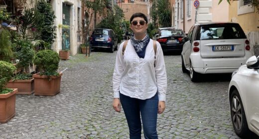 a woman stands on a cobblestone street in Italy.