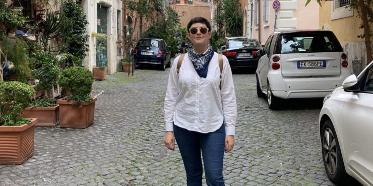 a woman stands on a cobblestone street in Italy.