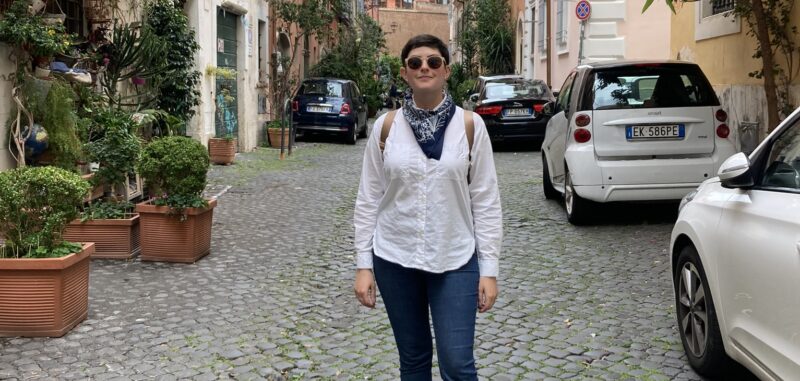a woman stands on a cobblestone street in Italy.