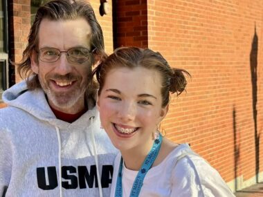 A man and his daughter smile for a photo.