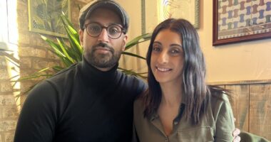 A couple (man and woman) sit together at a dinner table.