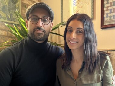 A couple (man and woman) sit together at a dinner table.