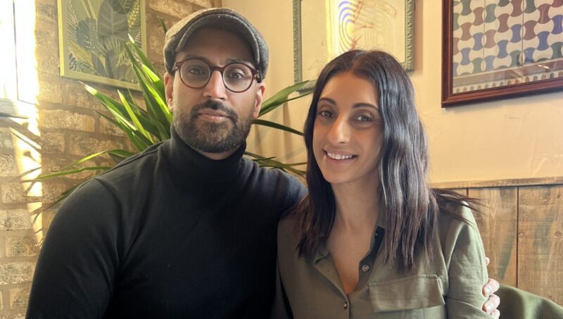 A couple (man and woman) sit together at a dinner table.