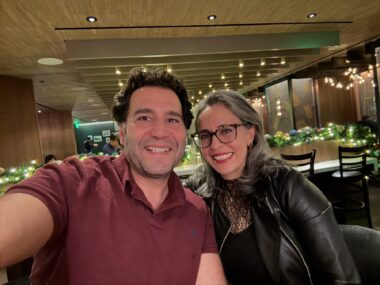 A man and woman lean together and smile for a photo inside of a club on New Year's Eve.