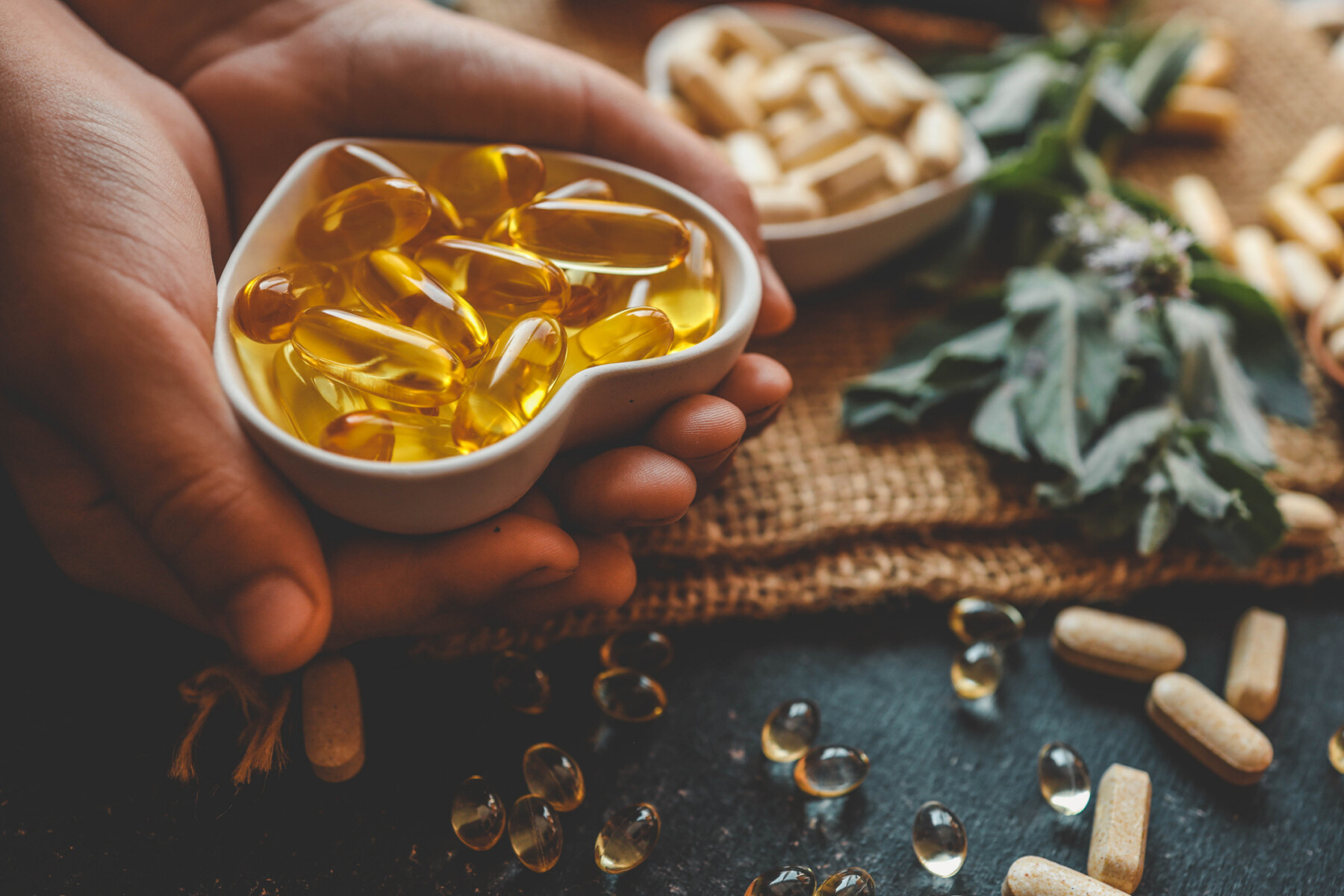 A hand holds vitamin D softgel capsules, representing vitamin D supplementation studied for MS relapse risk.