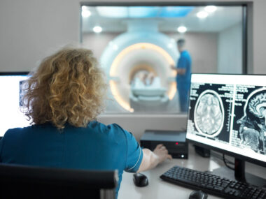 Close-up rear view of a female technician during an MRI scanning procedure,