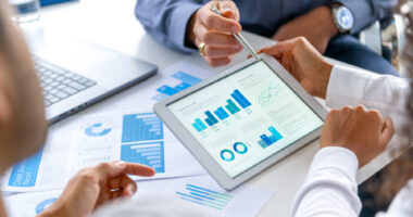 Three people sit at a table looking at graphs and charts.