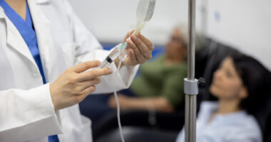 A doctor puts medicine into an IV drip.