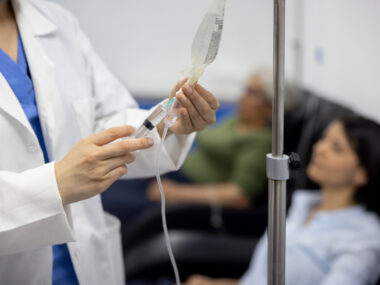 A doctor puts medicine into an IV drip.