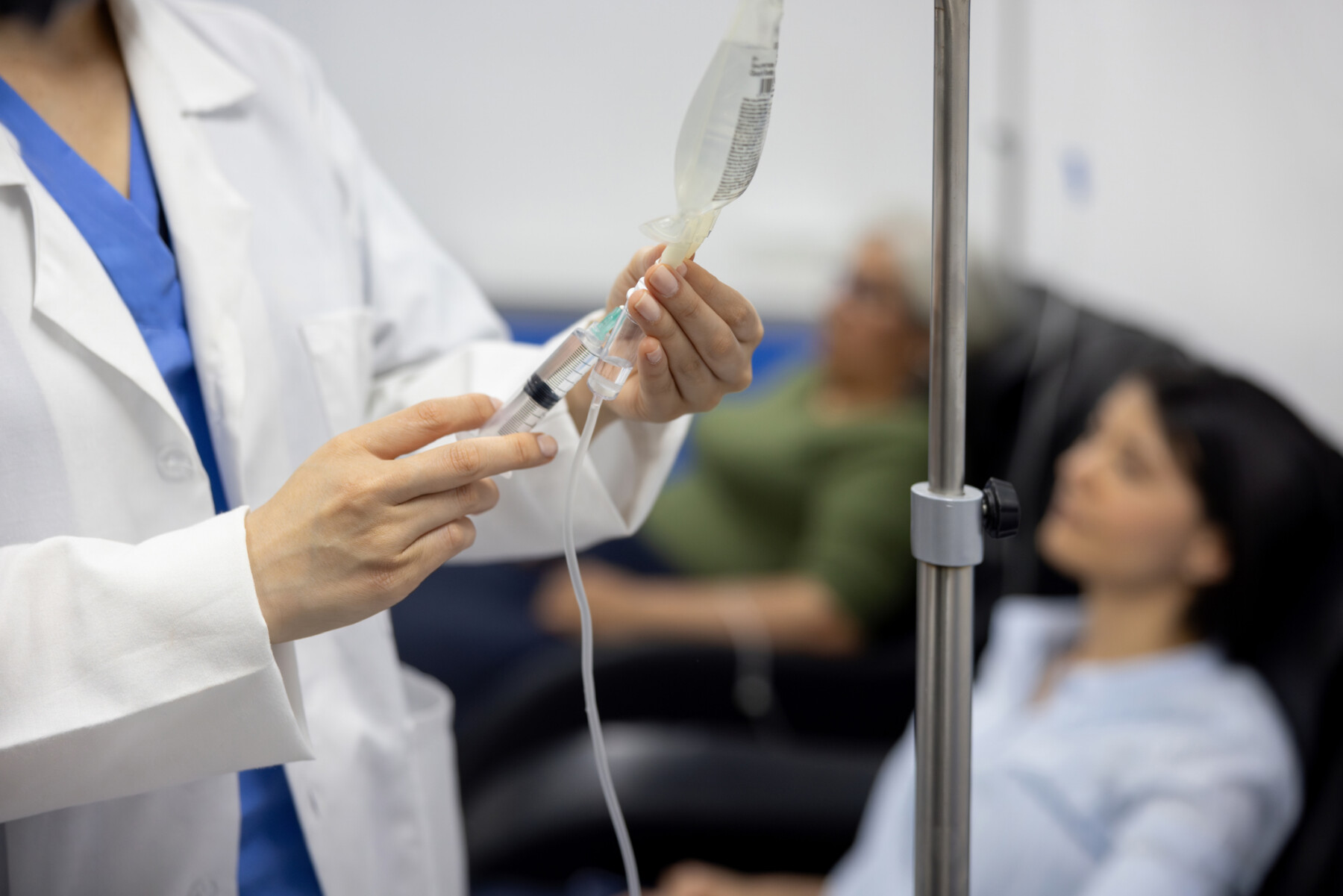 A doctor puts medicine into an IV drip.