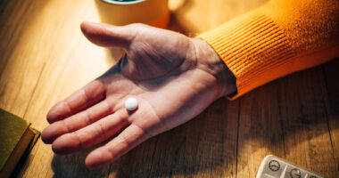 A photo shows a hand holding a pill.