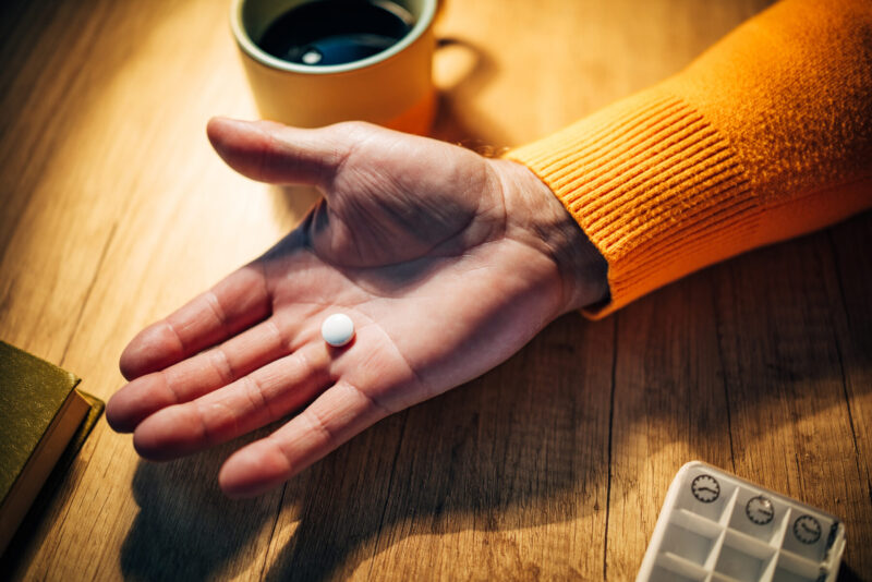 A photo shows a hand holding a pill.