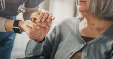A nurse holds the hand of a patient.