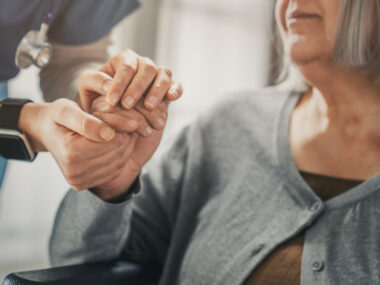 A nurse holds the hand of a patient.