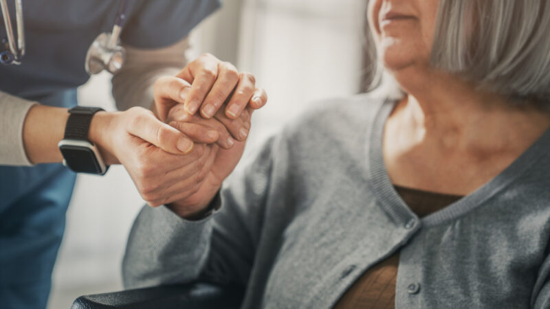 A nurse holds the hand of a patient.